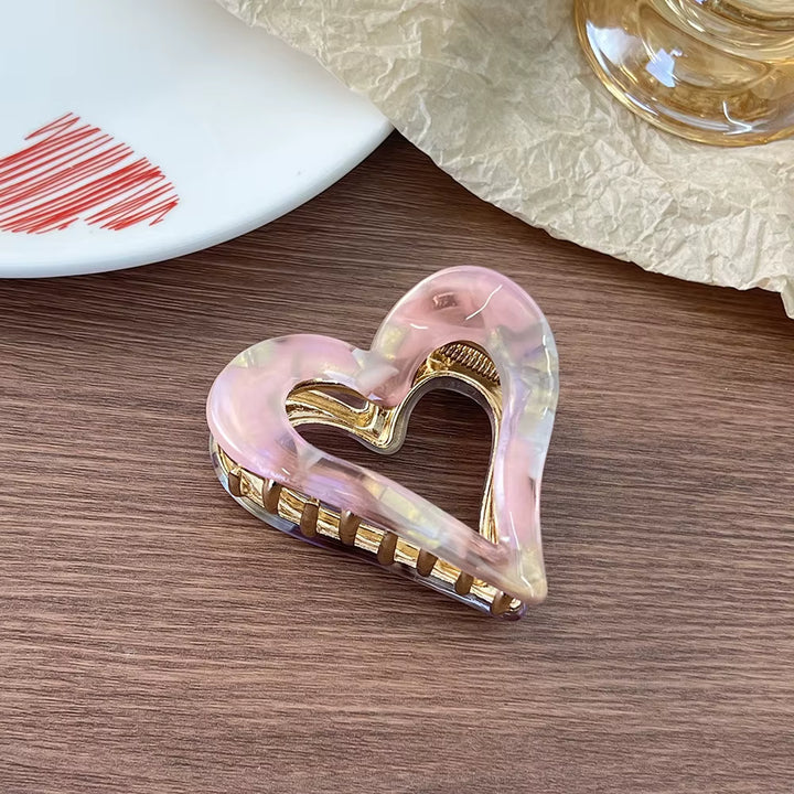 Amber-colored heart-shaped claw clip with gold-tone accents and a textured, marbled design.