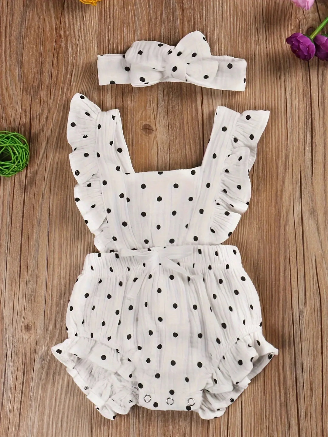 White polka dot baby romper with ruffled sleeves and headband.