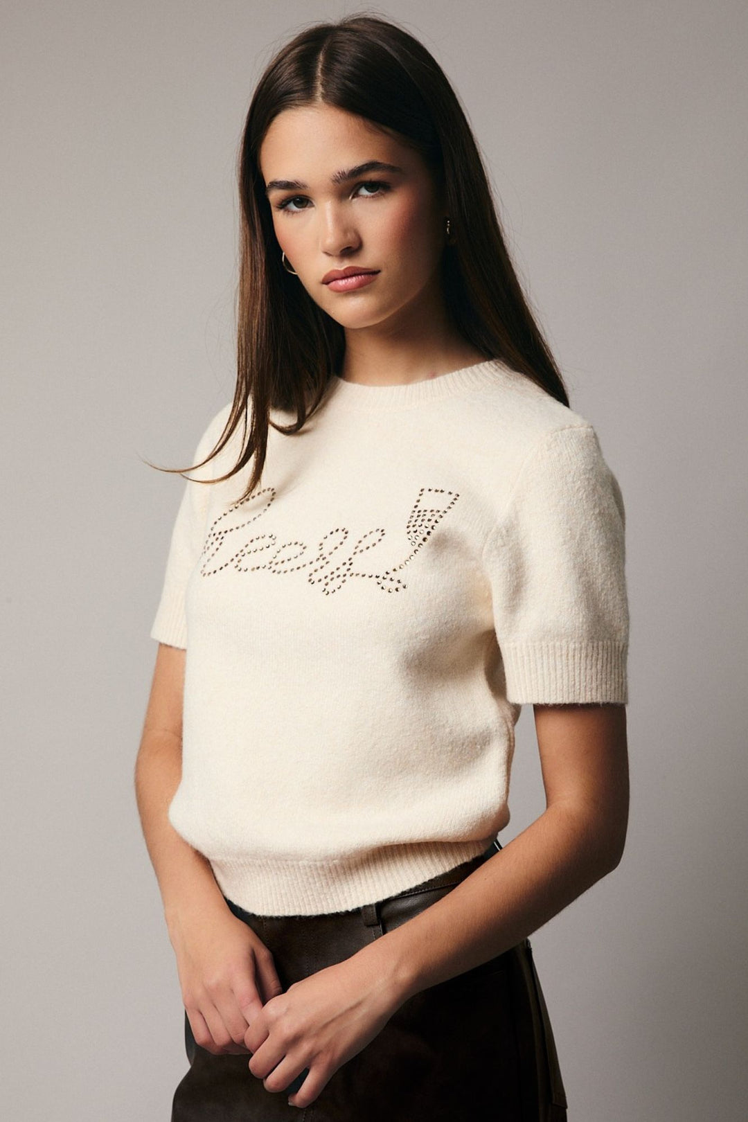 A white sweater with "Beverly" written in rhinestones across the front, modeled by a woman with long dark hair.