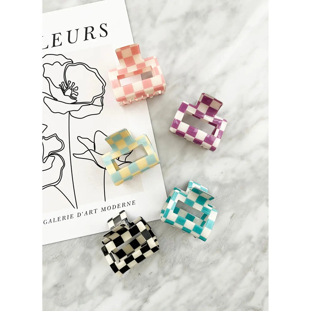 Assorted checkered hair claw clips in various pastel colors, showcased on a marble background.