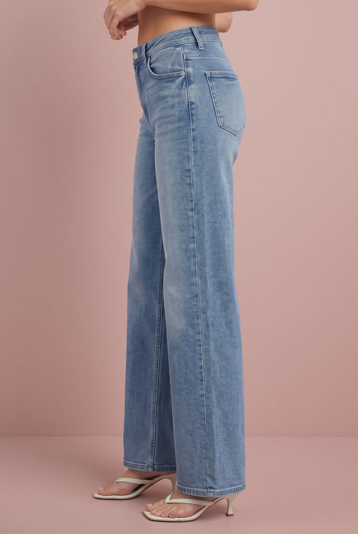 Light wash wide-leg jeans with high waist, side view on model wearing cream sandals.