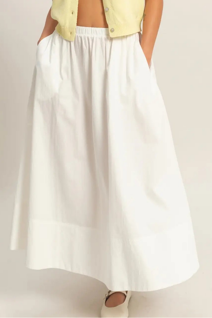 White skirt worn by a person on a plain background