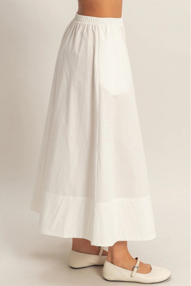 White skirt worn by a person on a plain background