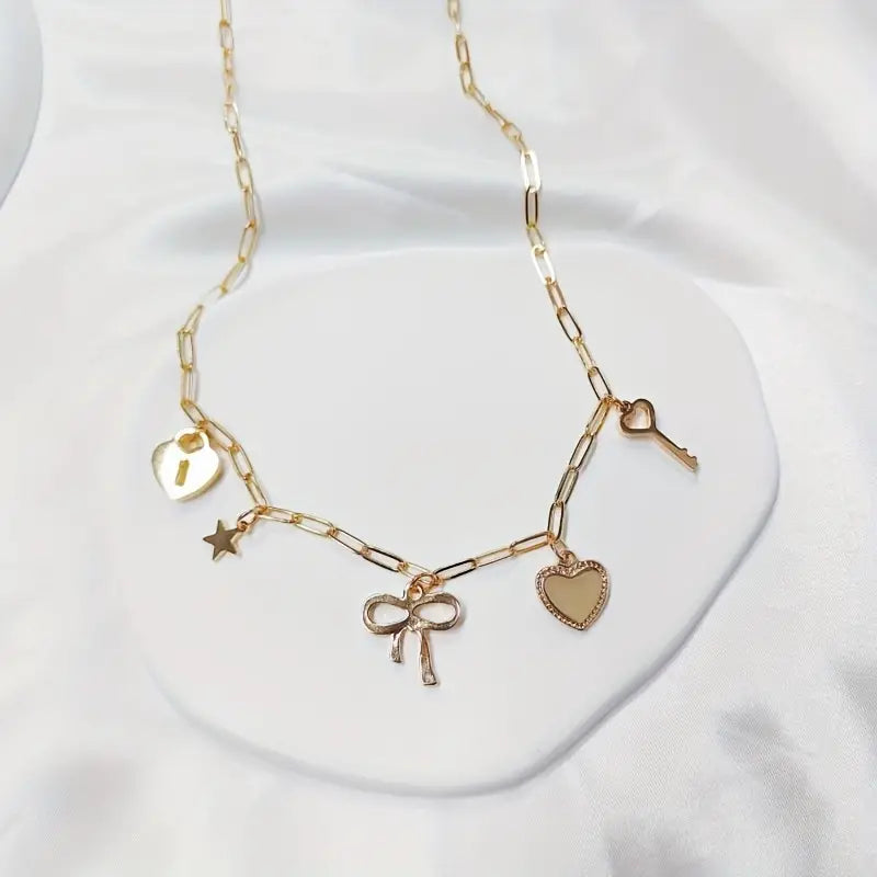A delicate gold-tone chain necklace featuring charms with a heart, star, and bow design.