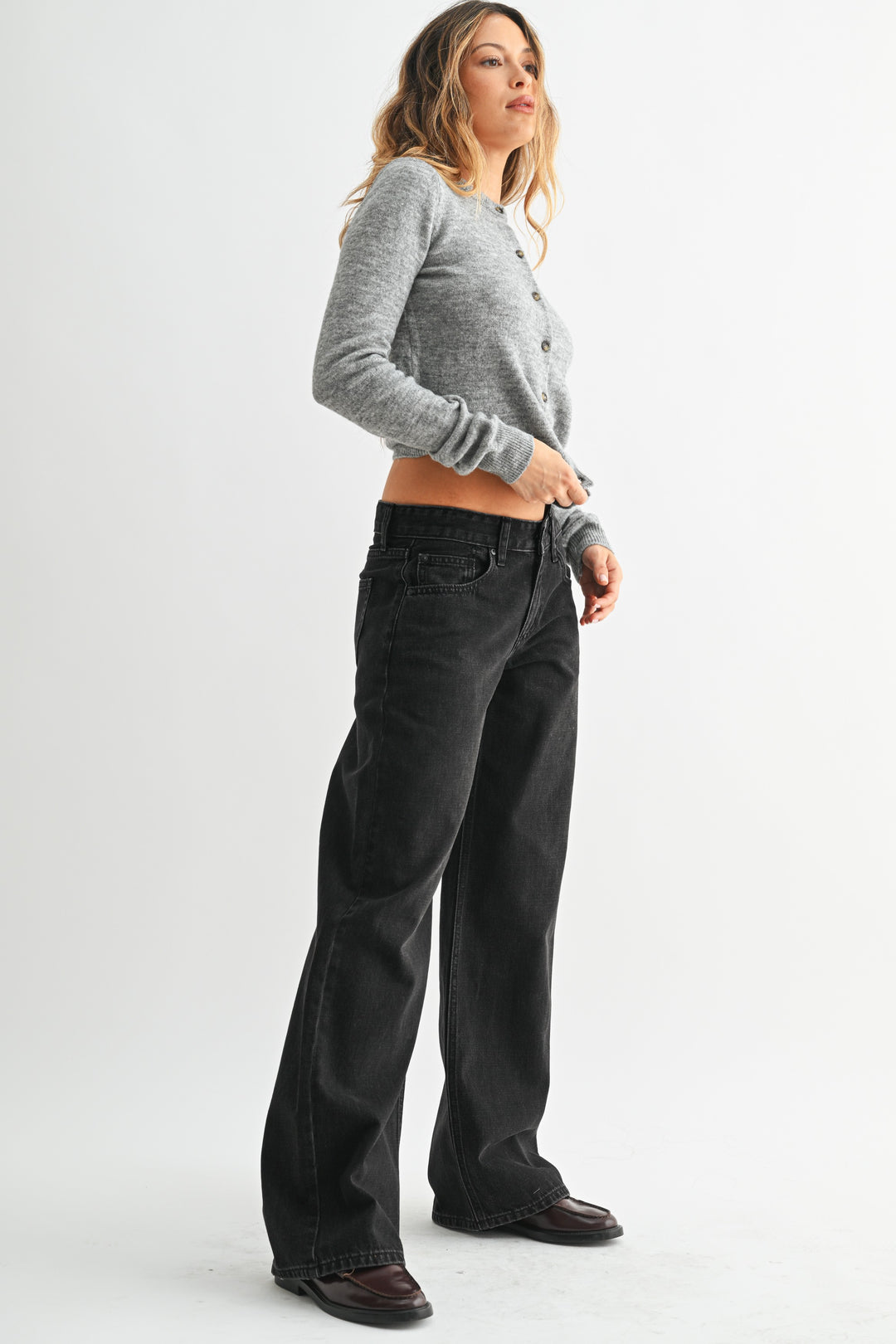 Woman wearing gray knit sweater and black wide-leg denim jeans with a relaxed fit.
