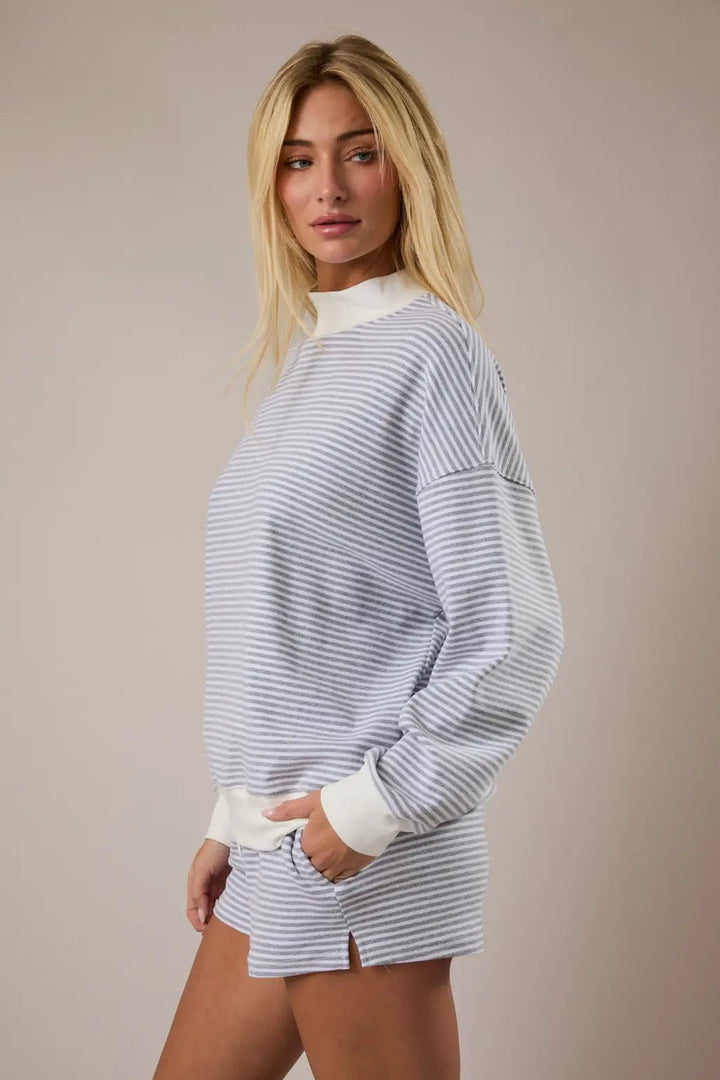 A white and gray striped mock neck sweatshirt with a relaxed, oversized fit and long puffed sleeves.