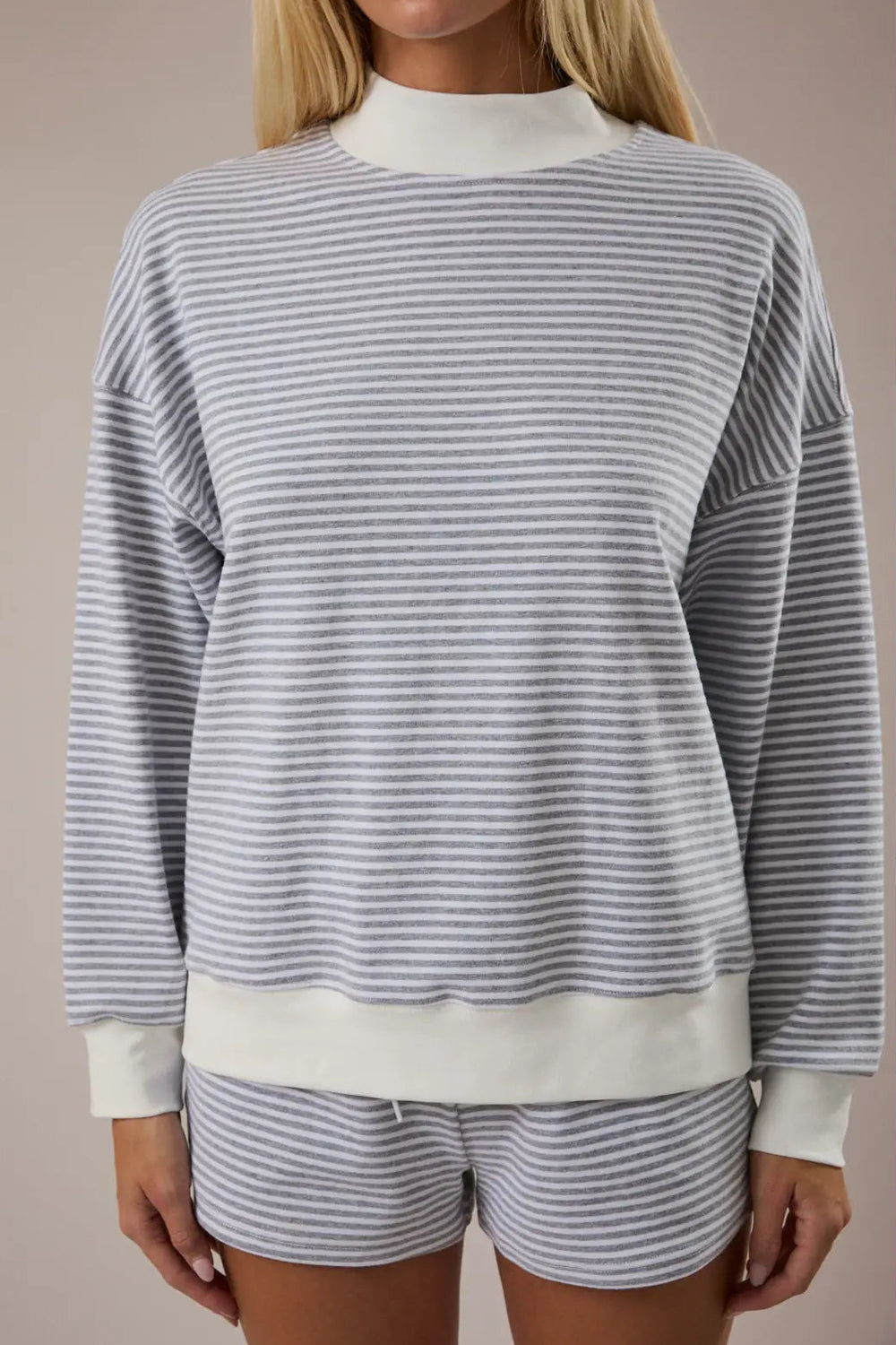 A gray and white striped mock-neck sweatshirt with a relaxed, casual fit and long sleeves.