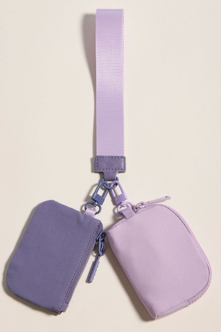Two-tone coin purse wristlet with zippered pouches and adjustable strap, in a light and dark purple color scheme.