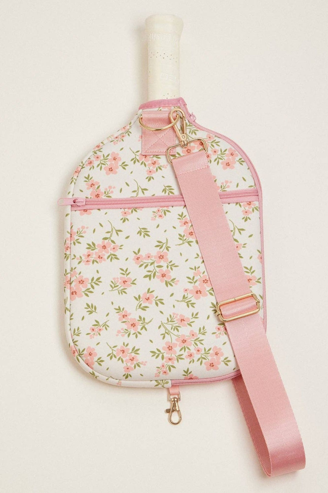 A floral-patterned, neoprene paddle bag with a pink strap and gold-tone hardware, designed to conveniently carry pickleball equipment.