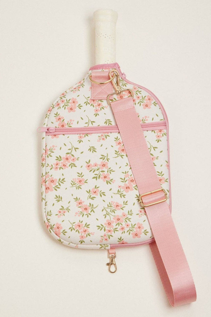 A floral-patterned, neoprene paddle bag with a pink strap and gold-tone hardware, designed to conveniently carry pickleball equipment.
