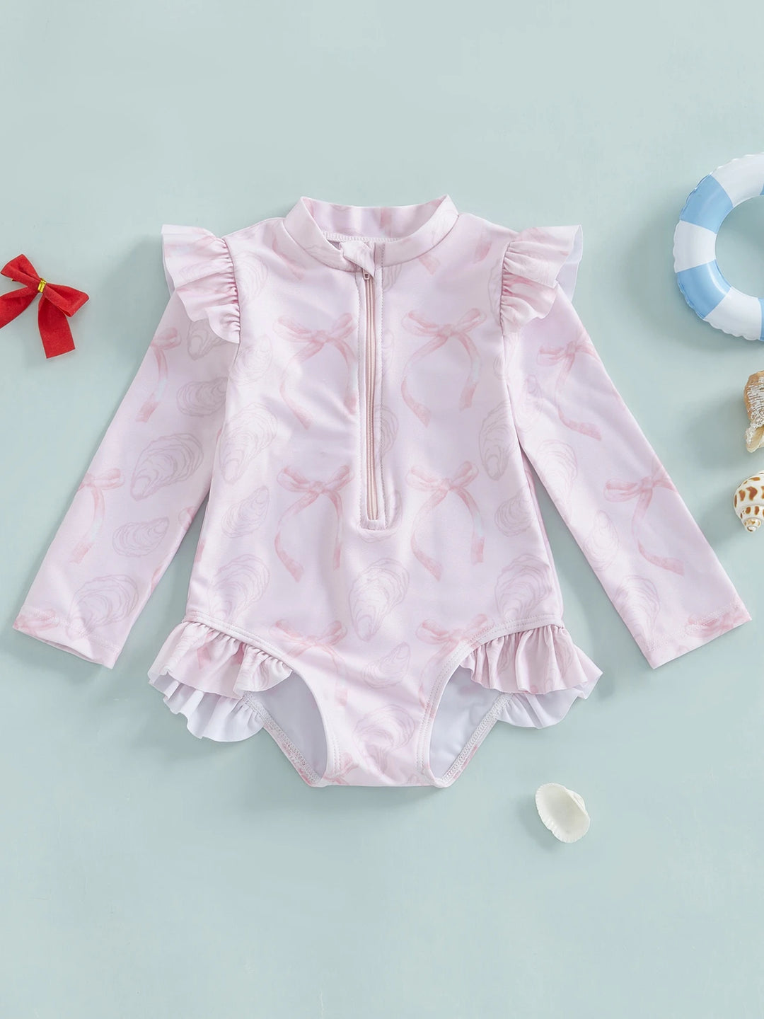 Delicate pink-patterned girls' rashguard swimsuit with ruffle trim and zip front closure.