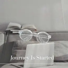 An open book, glasses, and a laptop on a wooden table with the text "Journey Is Started" displayed.