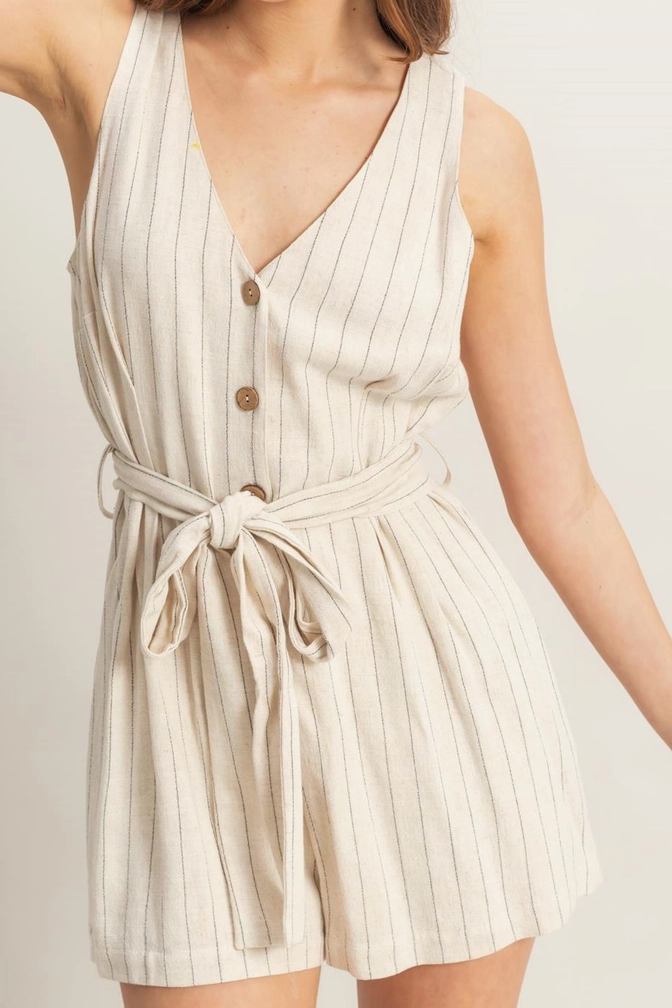 A sleeveless, beige striped romper with a plunging V-neckline, button front, and self-tie waist.