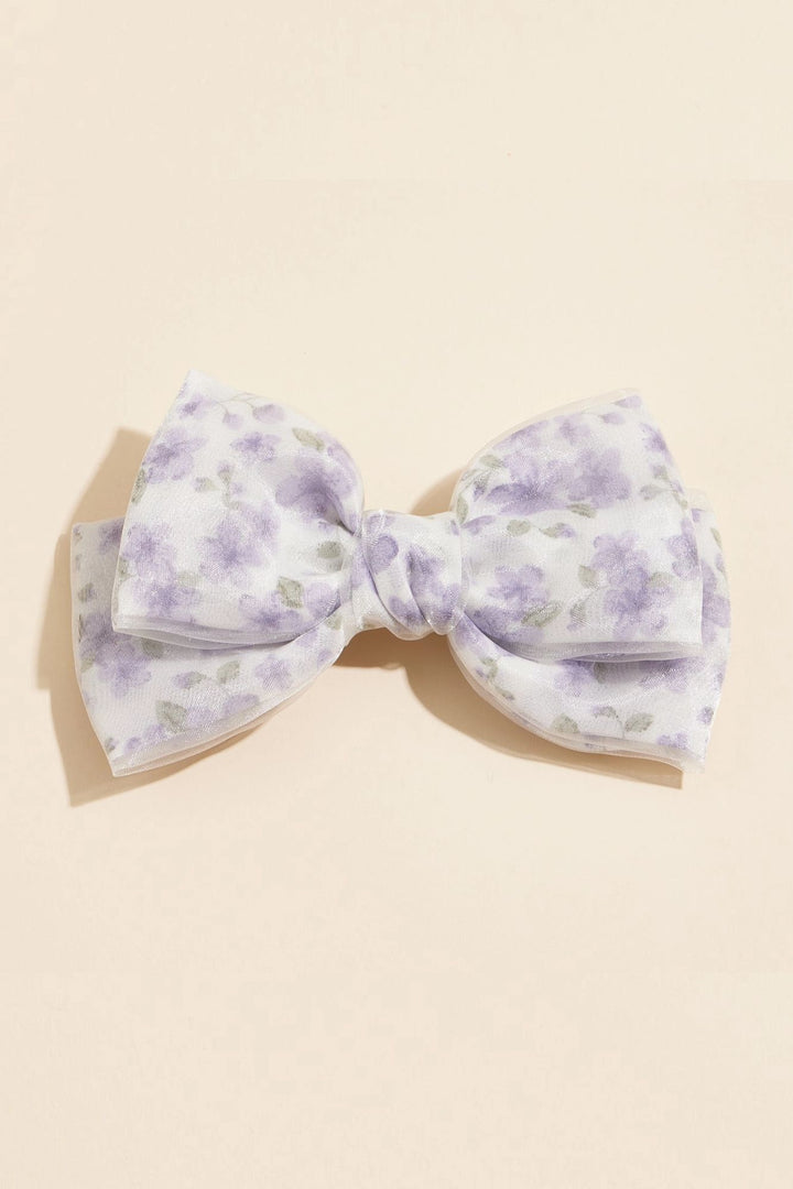 A large white floral bow hair clip with delicate purple and gray floral patterns, creating a romantic and whimsical accessory.