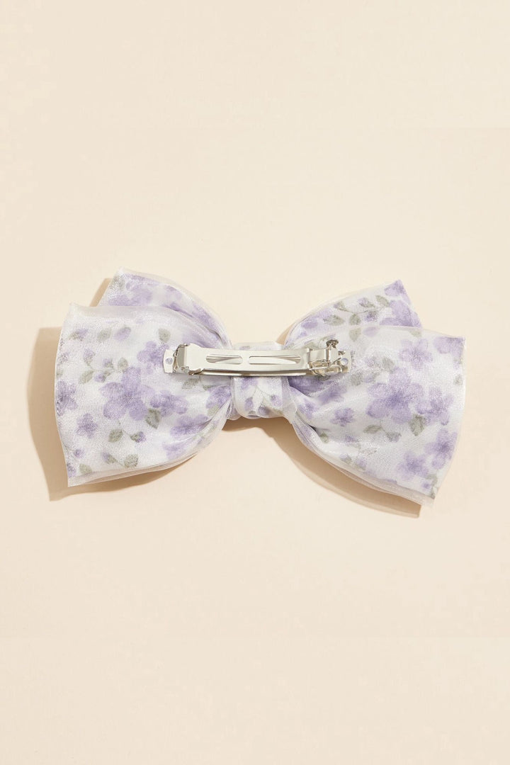 Soft lavender floral bow hair clip with silver metal clasp, adding a romantic, whimsical touch to hairstyles.
