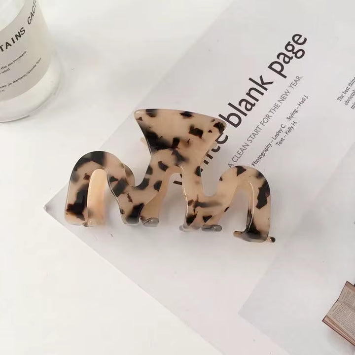 Three brown and cream tortoiseshell-patterned plastic hair claw clips of varying sizes.