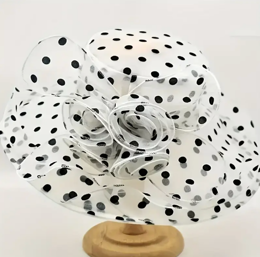 White derby hat with black polka dots on a wooden base.
