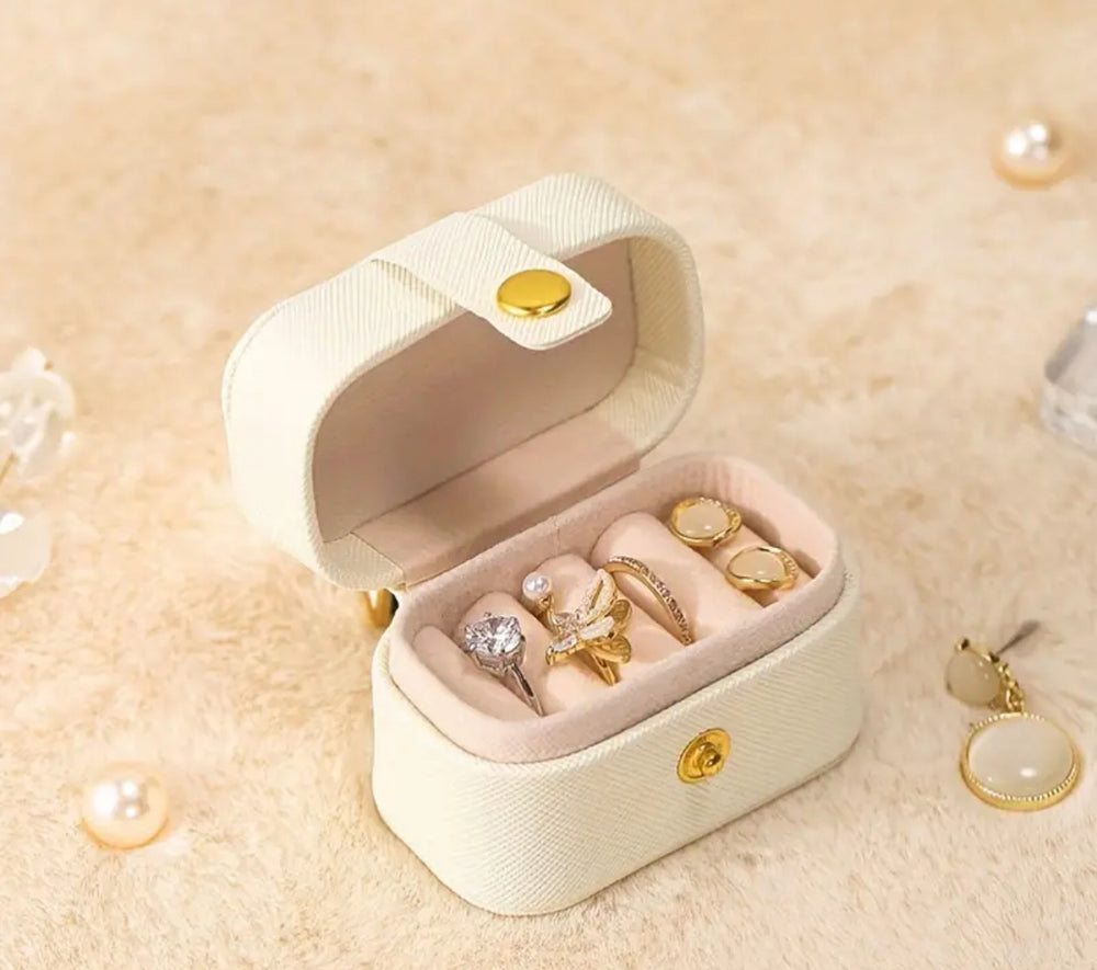 Elegant white jewelry box with gold accents, containing a variety of stylish rings, necklaces, and earrings.