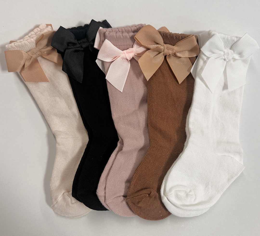 A set of scalloped, ribbed socks in beige, pink, black, brown, and white, each featuring a coordinating grosgrain bow detail.
