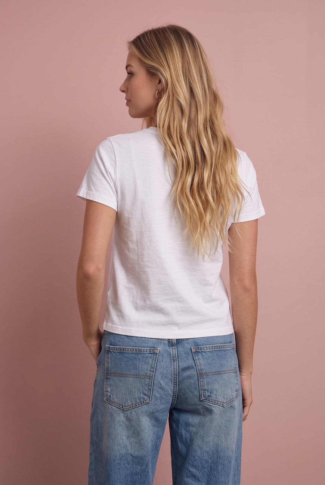 White cotton t-shirt worn with blue jeans, back view against pink background.