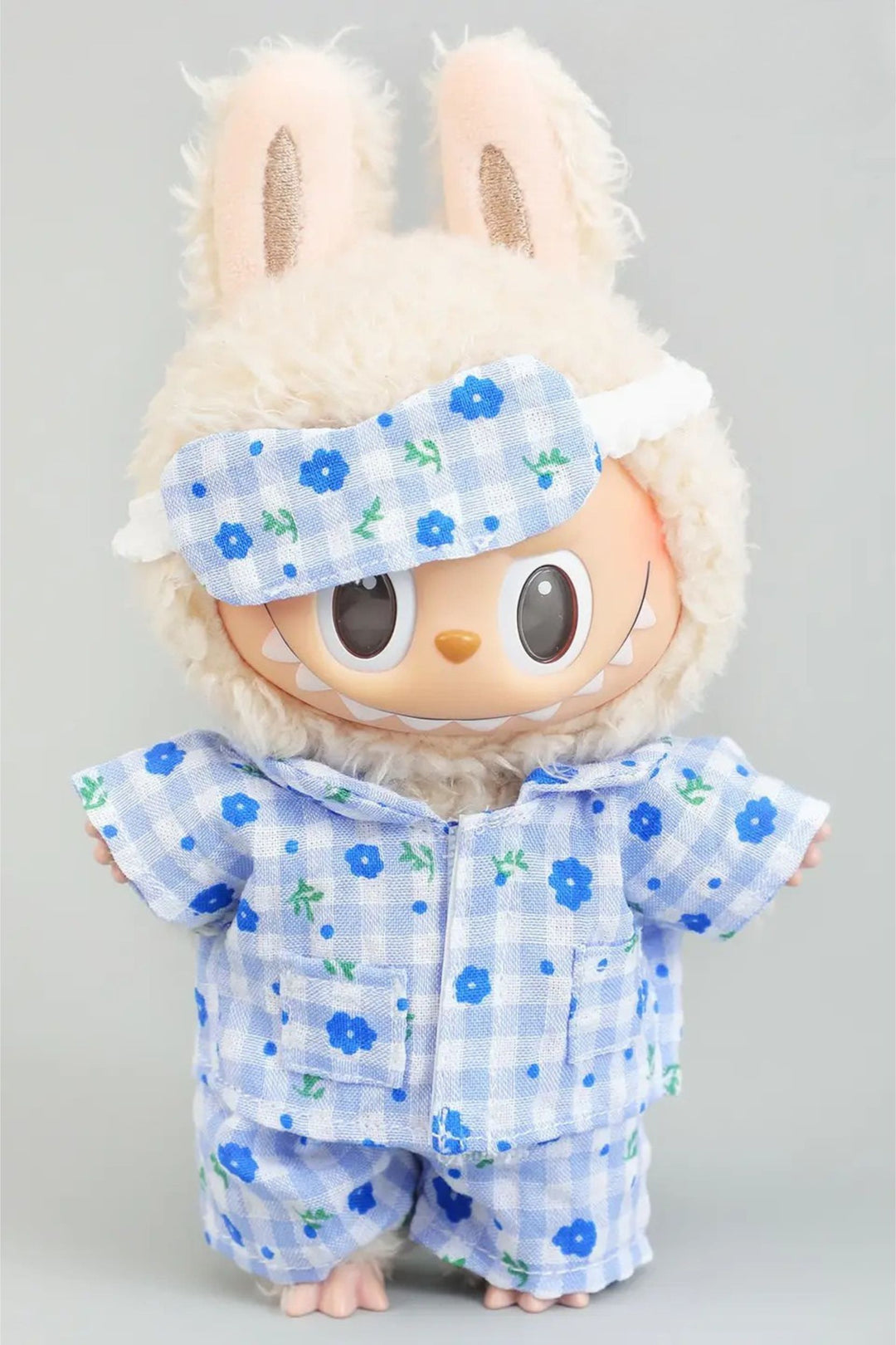 A fluffy white plush toy wearing a blue and white floral print pajama set and matching sleep mask.