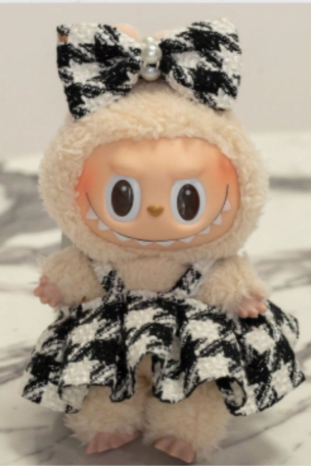 Plush toy with a checkered outfit and bow on a light background