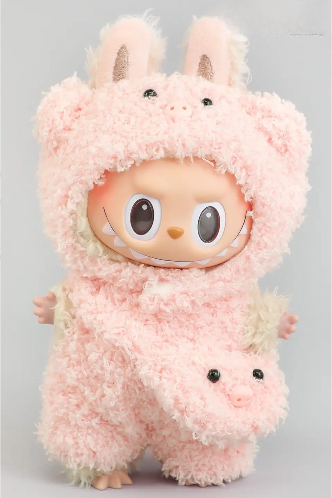 Soft pink plush toy with large eyes and perky ears, resembling a pig or rabbit-like creature, wearing a pink furry outfit with a zipper pouch in front.