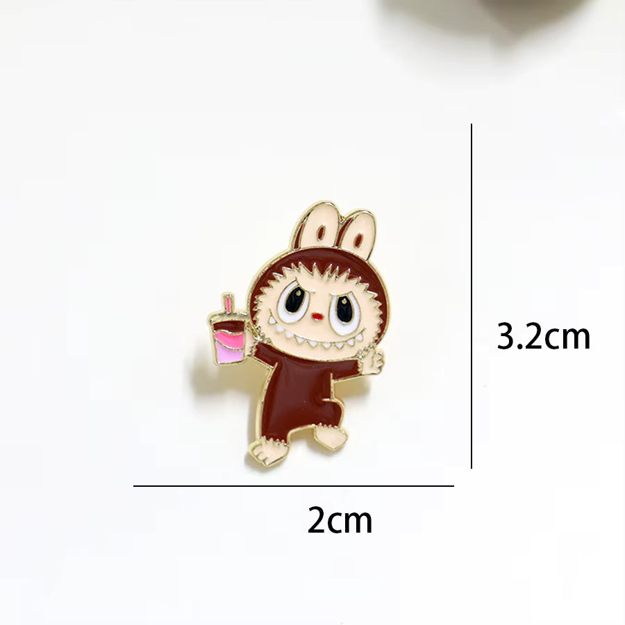 Whimsical cartoon character pin with large eyes and mouth, holding a pink drink, in shades of brown and pink.