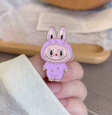 A whimsical lavender enamel pin depicting a cute, wide-eyed cartoon bunny character with large ears and a smiley face.