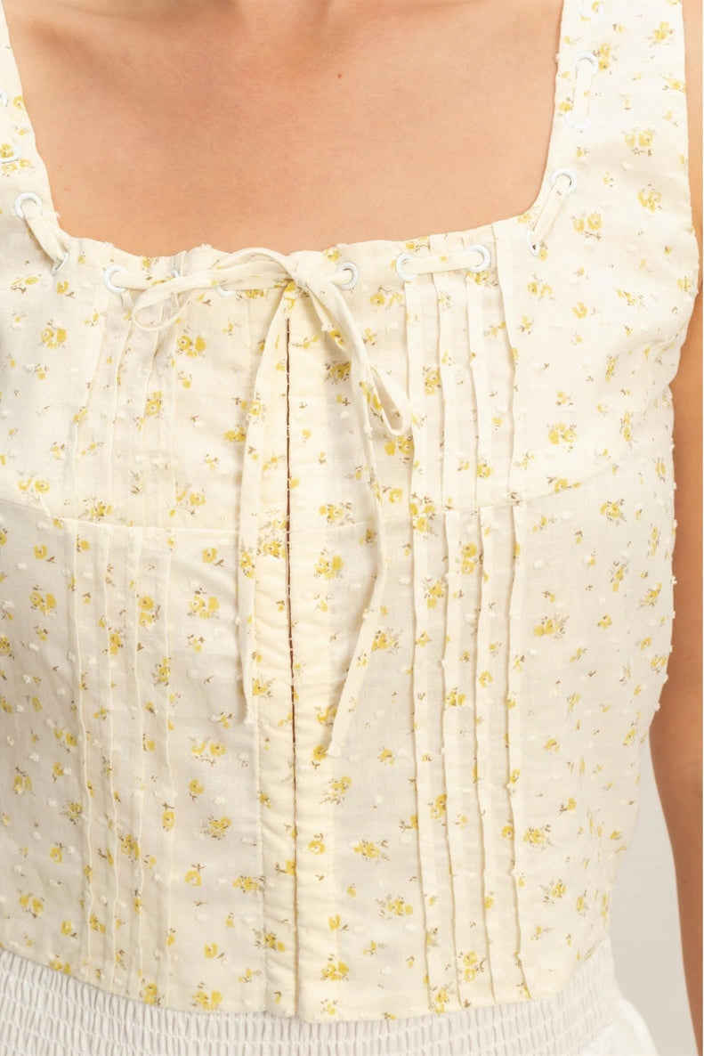 Ivory floral print crop top with adjustable tie waist and pleated bust detail.