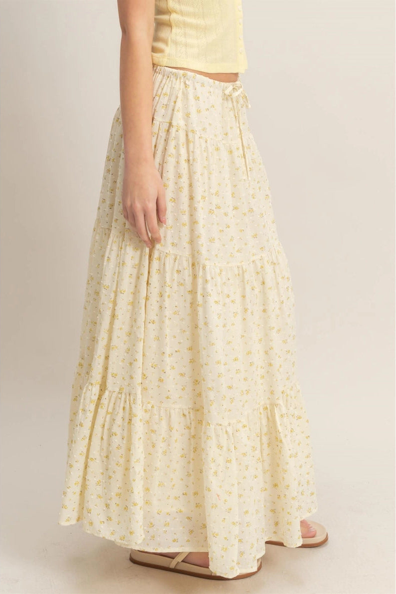 Flowing white skirt with a delicate yellow floral print and tiered ruffles, creating a feminine, airy look.
