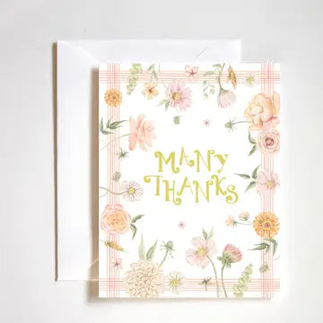 Floral greeting card with wreath of pink, peach, and white flowers surrounding golden "Many Thanks" text against a plaid background.