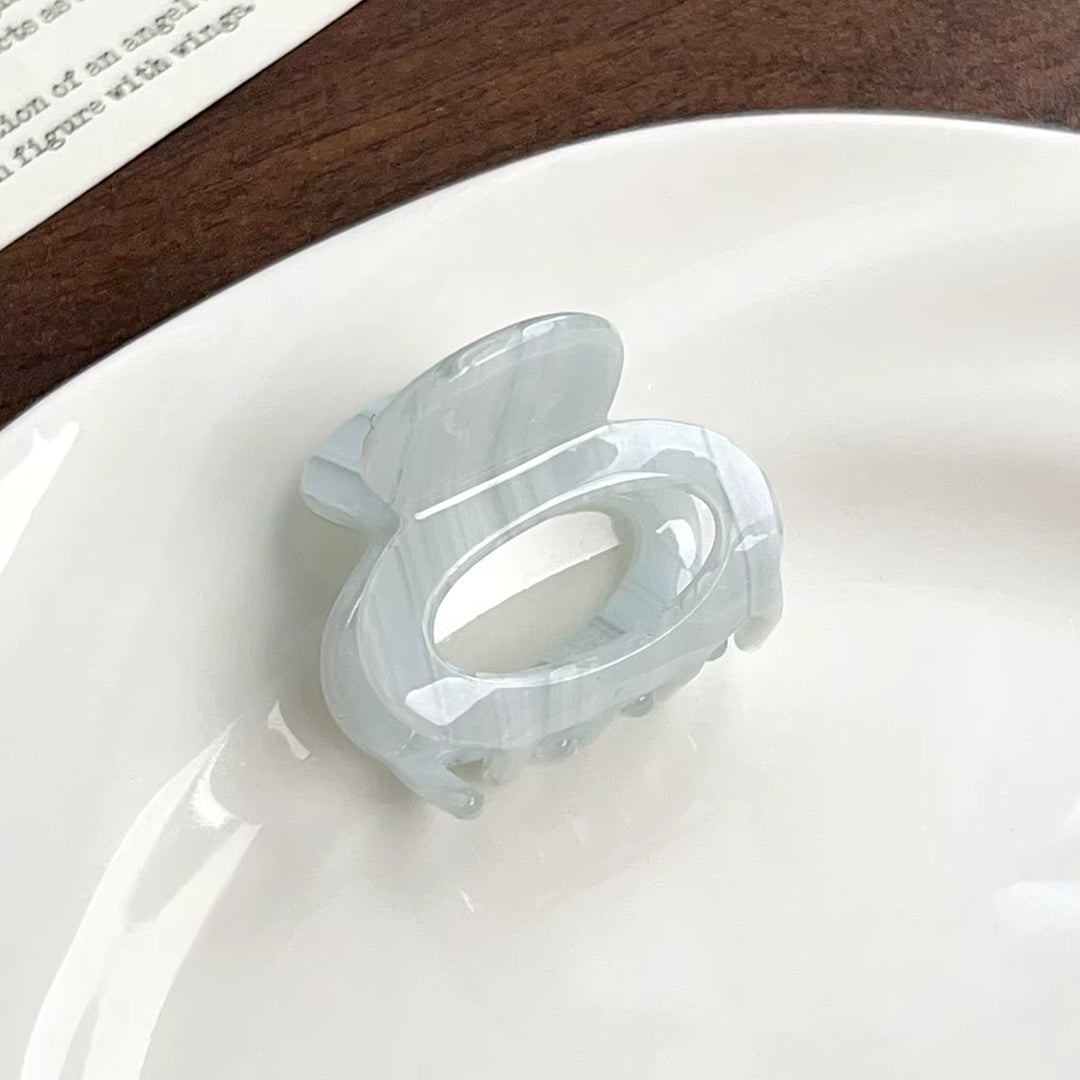 A translucent, oval-shaped claw clip with a unique, sculptural design.