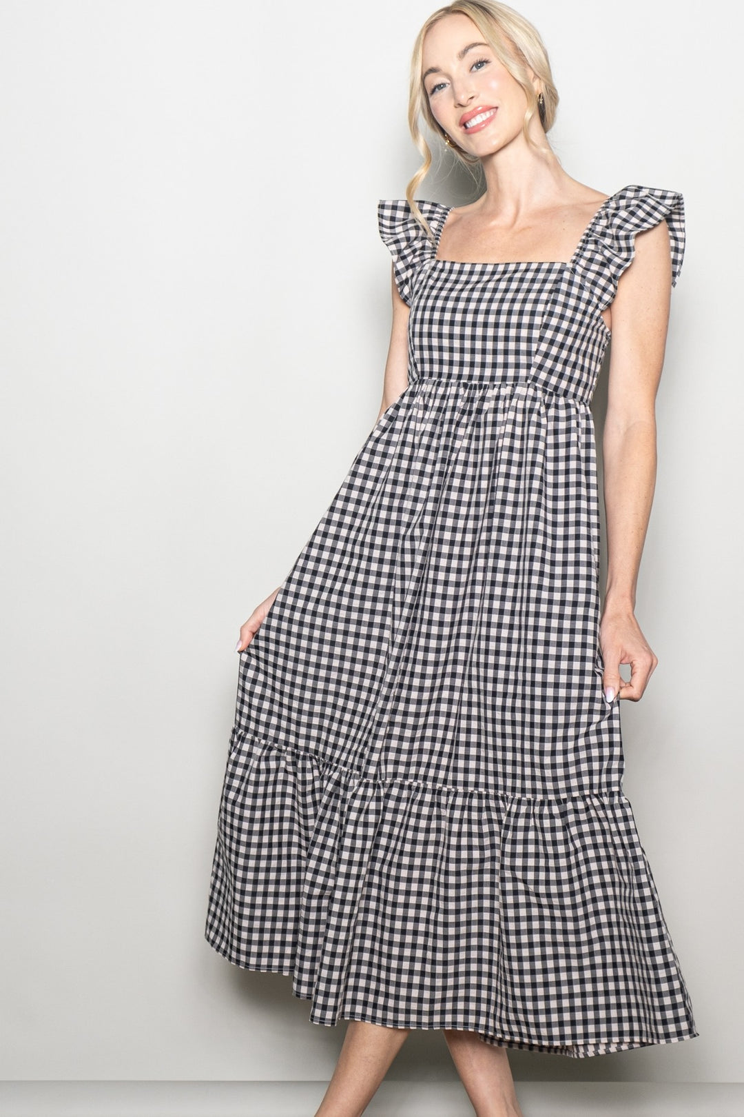Woman wearing a black and white checkered dress against a plain background