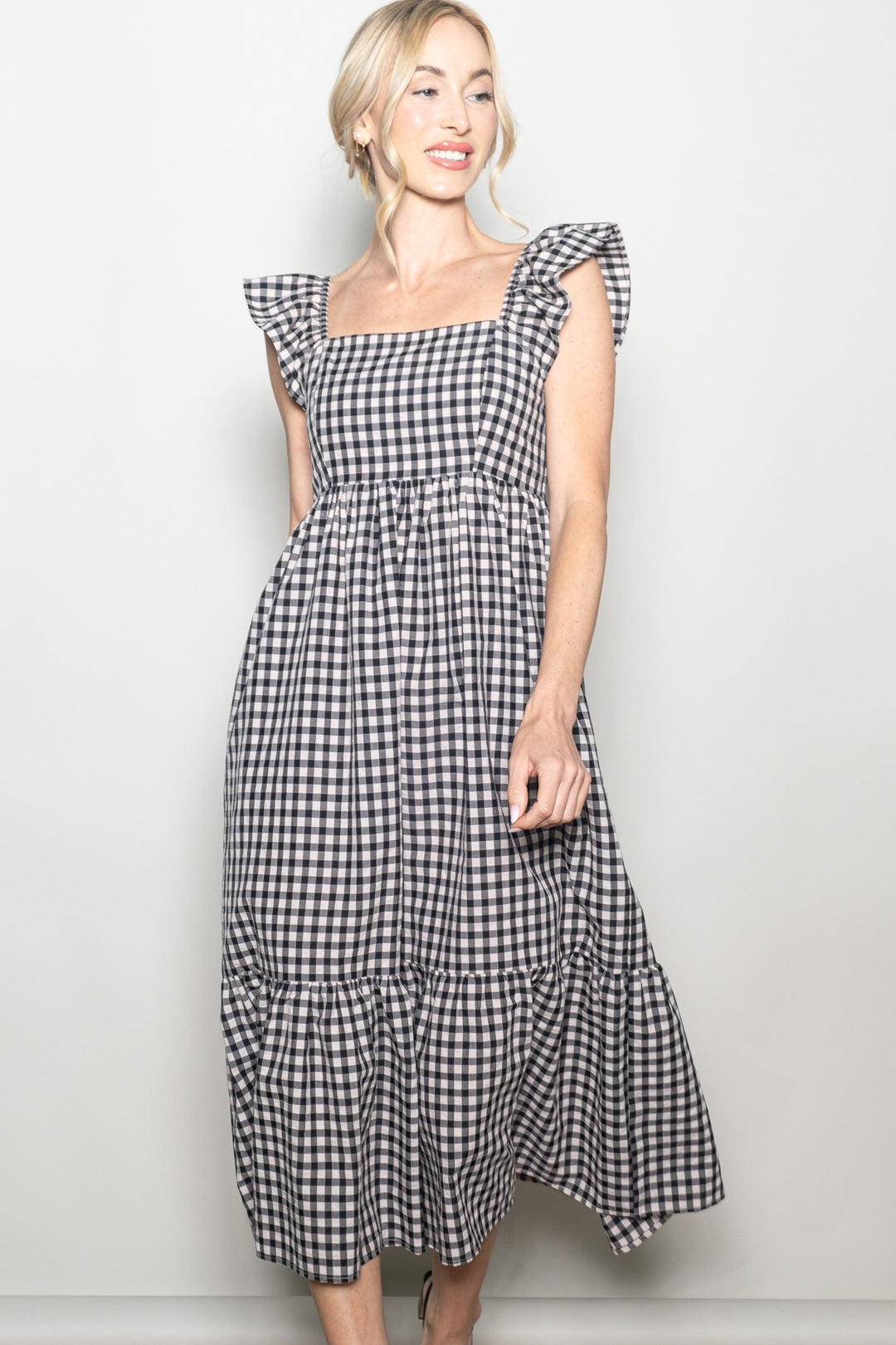 Woman wearing a black and white checkered dress against a plain background