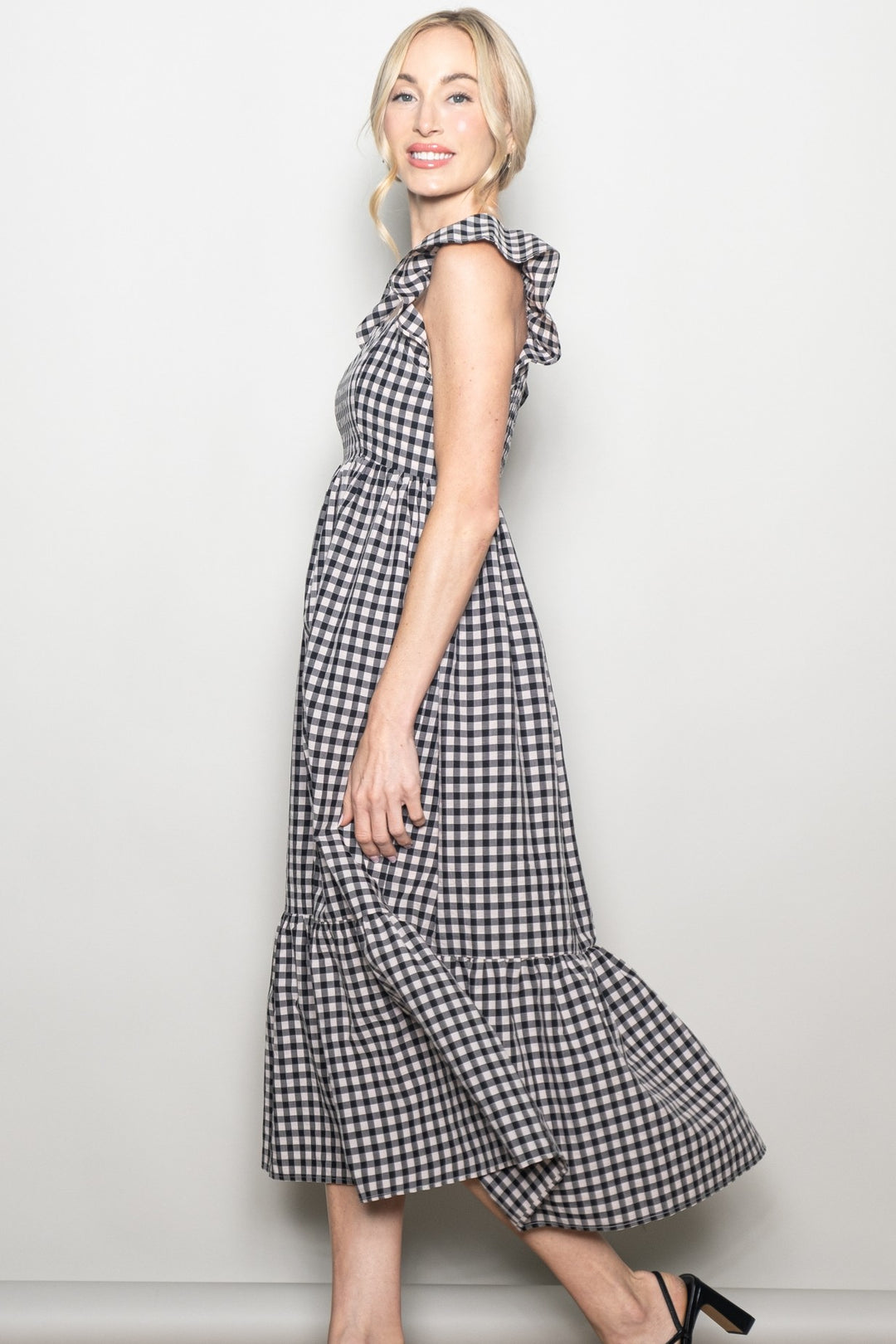 Woman wearing a black and white checkered dress against a plain background