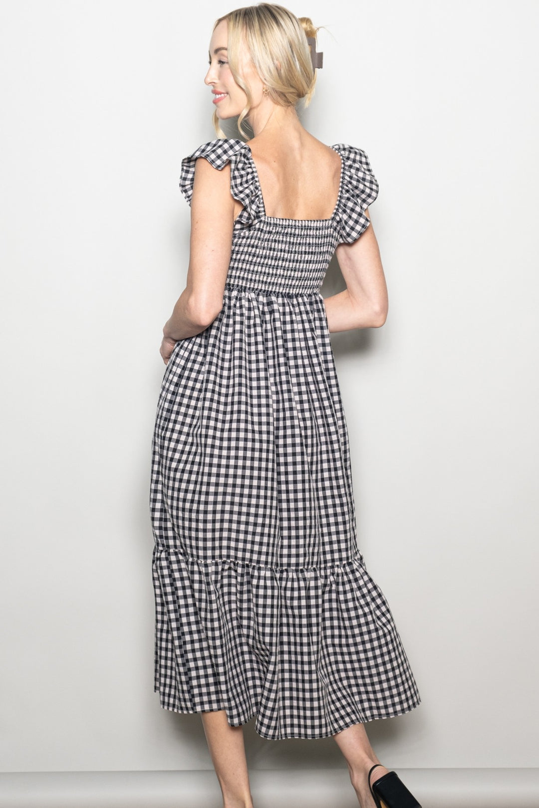 Woman wearing a black and white checkered dress against a plain background