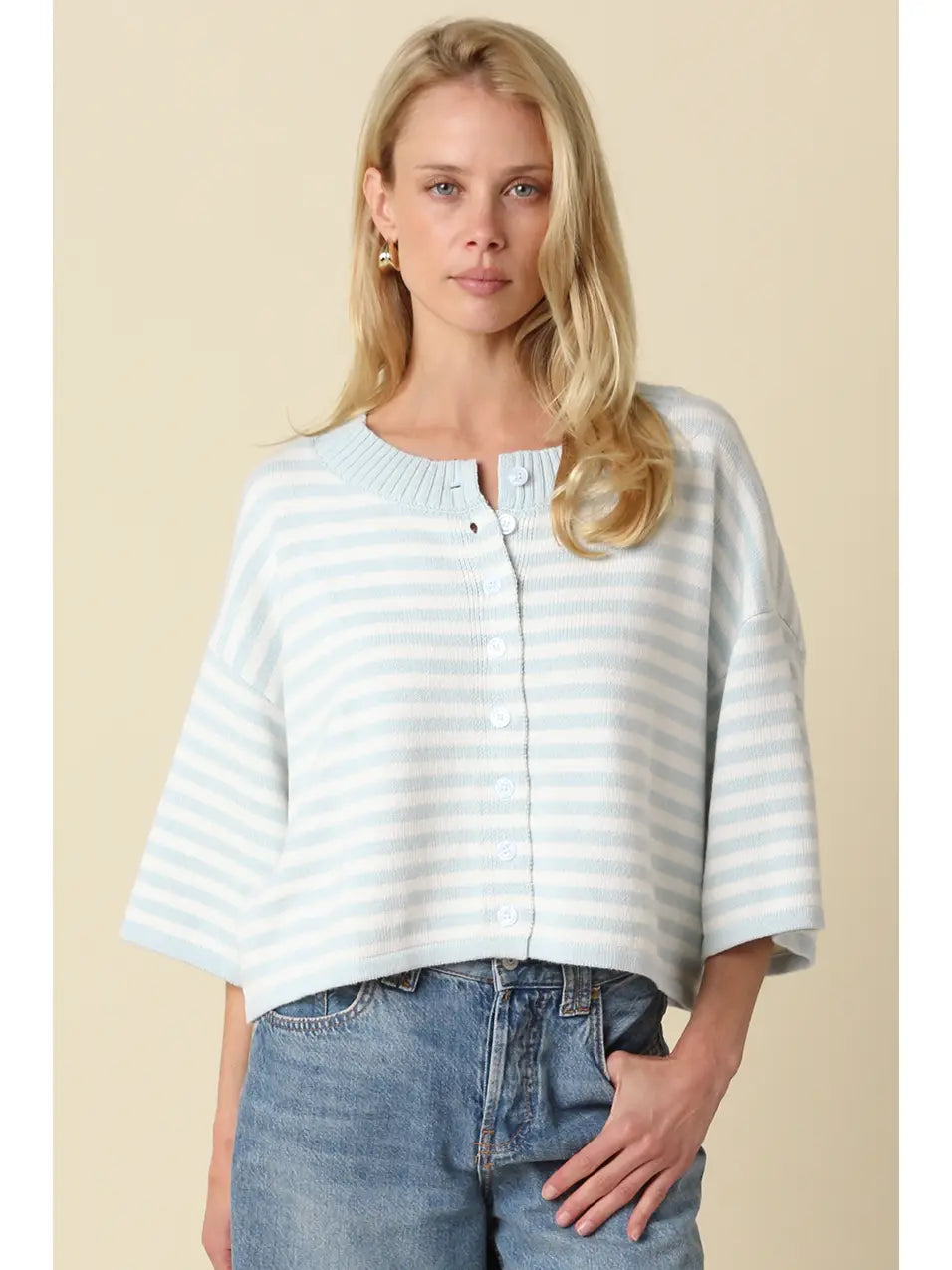 A light blue and white striped, loose-knit cardigan with a crew neckline and button-front closure, worn by a young blonde woman with wavy hair.