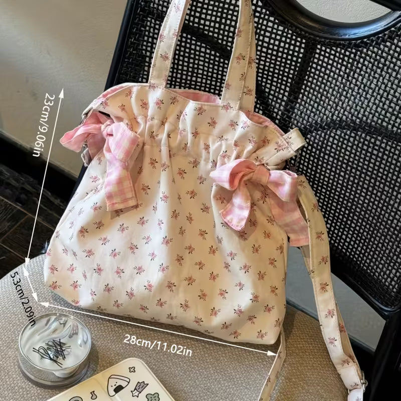 A floral print cloth pouch bag with pink bows and straps, measuring approximately 28cm by 11.02 inches.