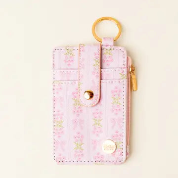 Pale pink keychain wallet with floral pattern, gold hardware, and zipper compartment.
