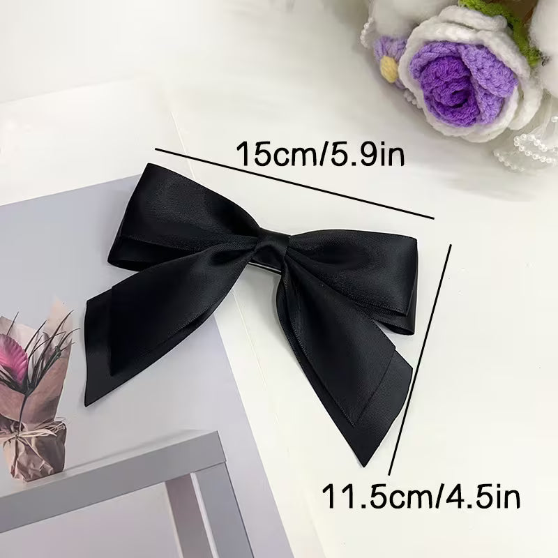 Black satin bow hair clip with dimensions 15cm wide and 11.5cm long.