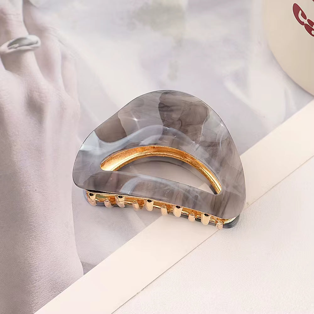 Raven semi-circle hair claw clip with gold metal accents and a transparent lucite design.