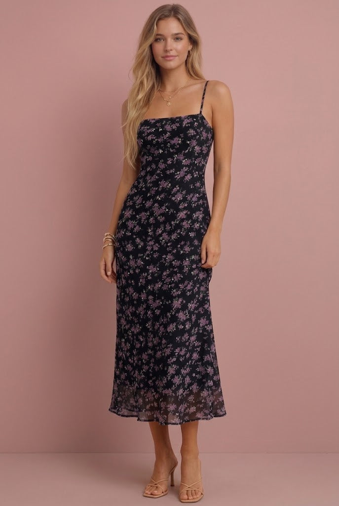 Black floral chiffon midi dress with thin straps on model against pink background.
