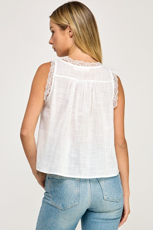 A white sleeveless top with lace trim, a babydoll silhouette, and a button-up back for a feminine, relaxed look.