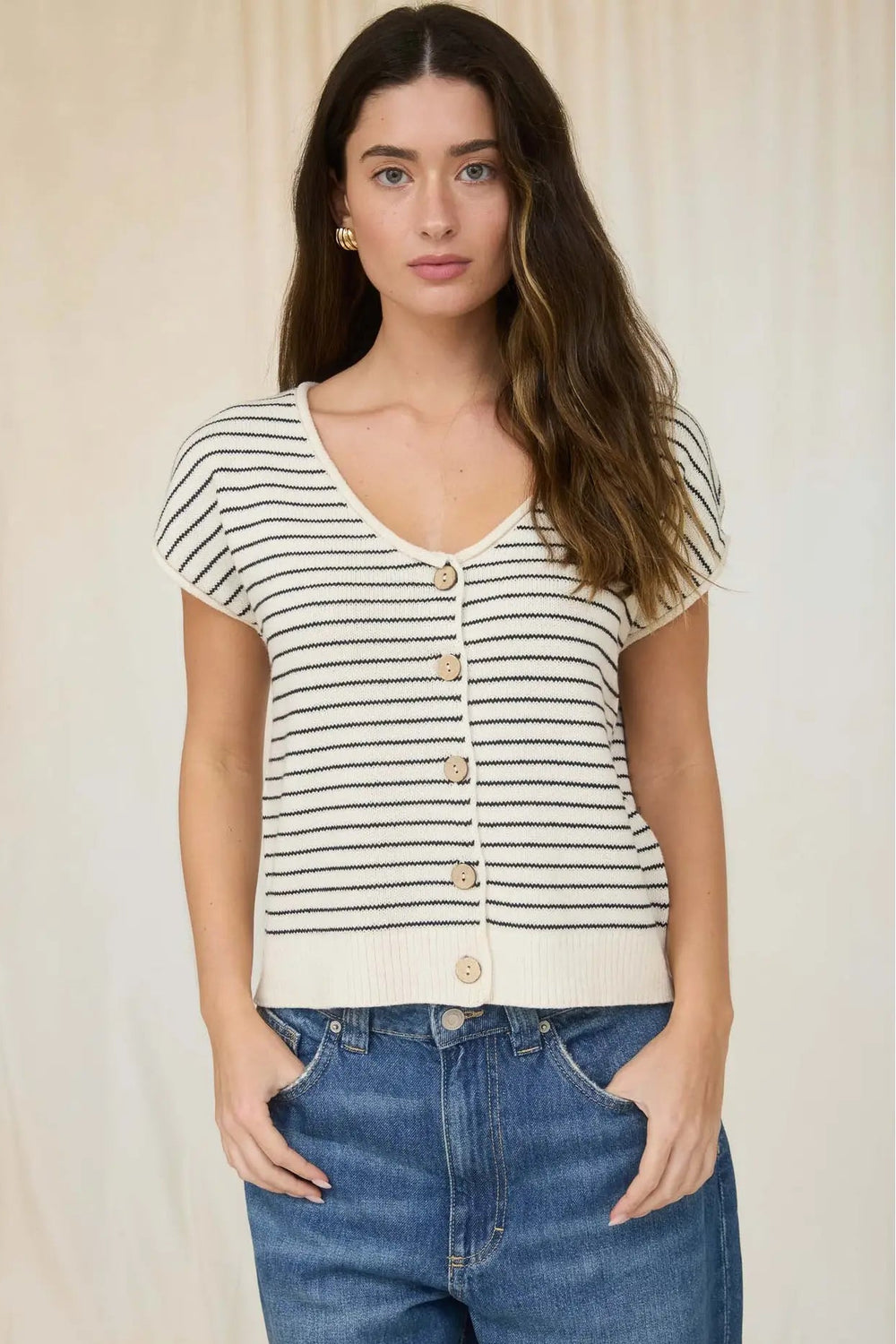 Woman wearing a striped shirt and jeans against a plain background
