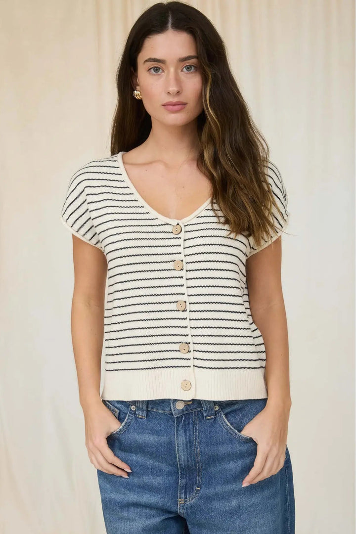 Woman wearing a striped shirt and jeans against a plain background