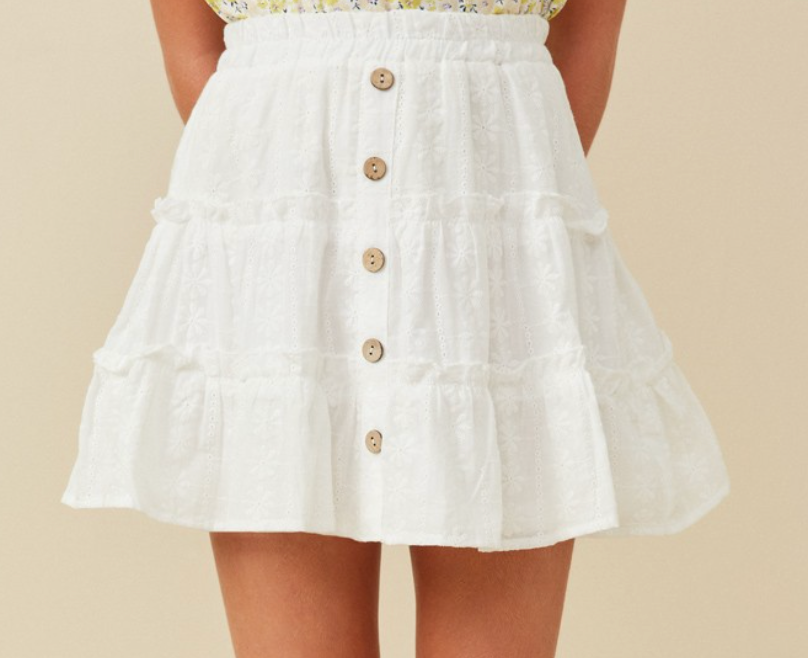 A white cotton mini skirt with a button-down front and ruffled tiers, designed for kids.