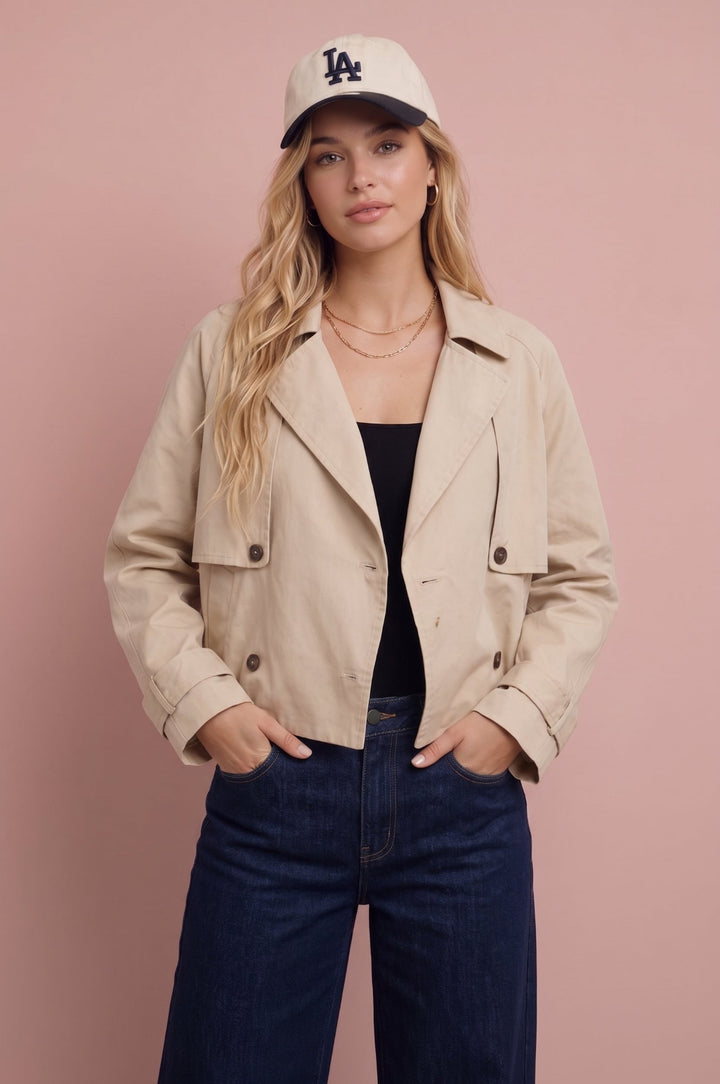 Beige cropped trench jacket worn with black top and dark jeans, front view.