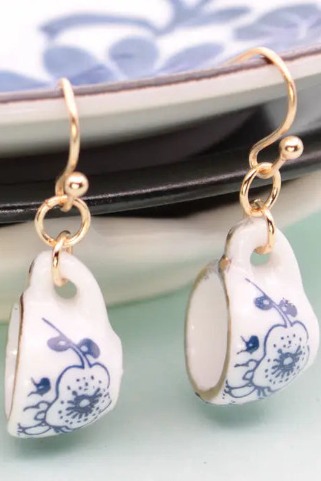Vintage ceramic teacup earrings with delicate floral patterns and gold trim, hanging from gold hooks.