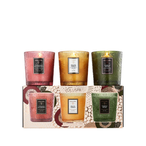 A set of three small scented candle jars in red, gold, and green colors, each featuring distinct floral designs on the exterior.